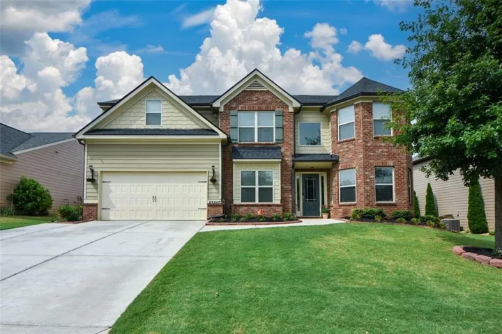 Two-story traditional residence featuring a brick and siding exterior, a two-car garage, and a bay window element