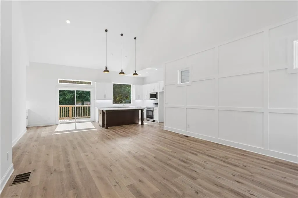 Expansive living area featuring vaulted ceilings, wood-finish flooring, and crisp white board and batten wall detailing