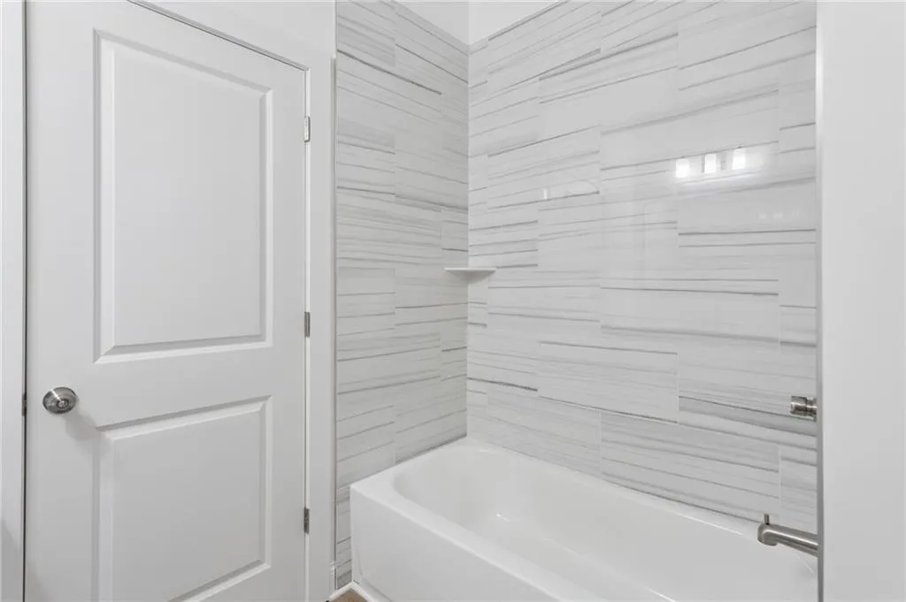 White panel door beside a bathtub with brushed nickel hardware