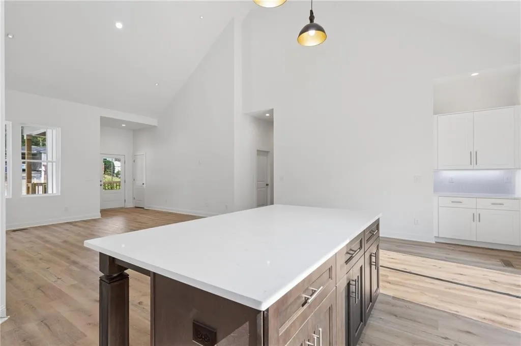 Spacious open-concept interior featuring a substantial island with a white countertop, recessed lighting, and wood-finish flooring