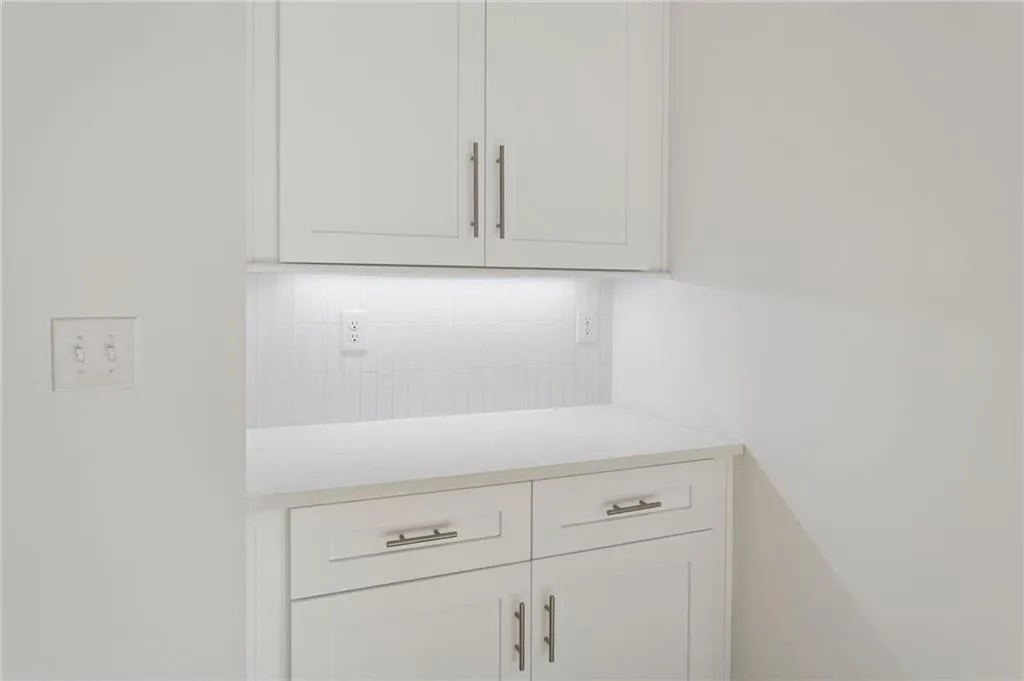 White shaker-style cabinetry with brushed nickel hardware, quartz countertop, and a white subway tile backsplash