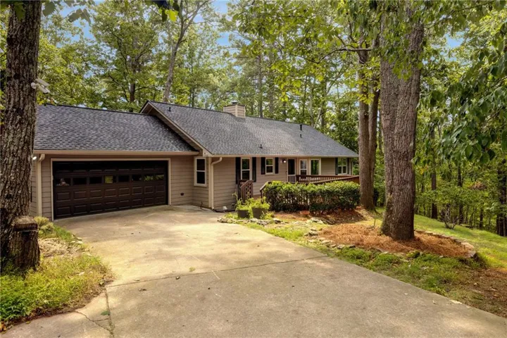 Siding exterior with a dark shingle roof and an attached garage with a panel door