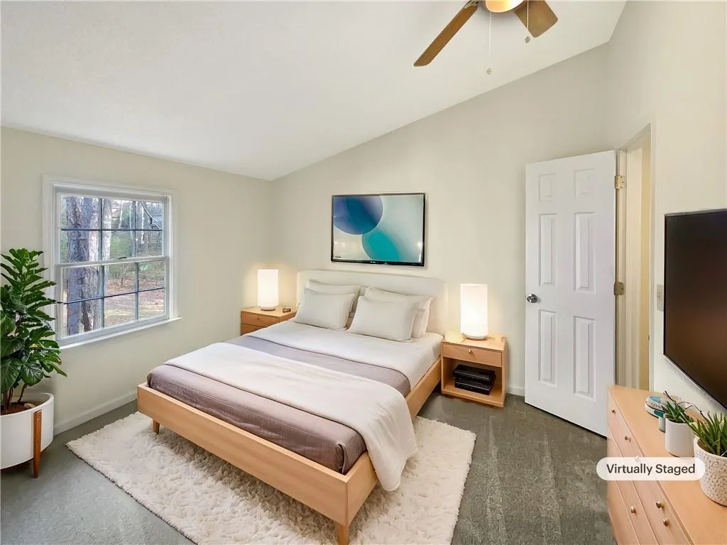 Bedroom featuring vaulted ceiling, dark colored carpet, and ceiling fan