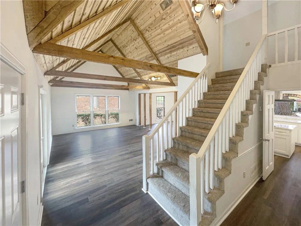 Staircase featuring wood finished floors, a wood ceiling with exposed beams, a high ceiling, and a chandelier