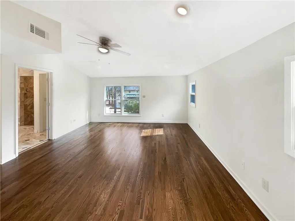 Empty room with dark wood-style floors and ceiling fan