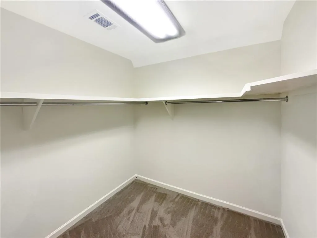 Walk in closet with dark carpet and lofted ceiling