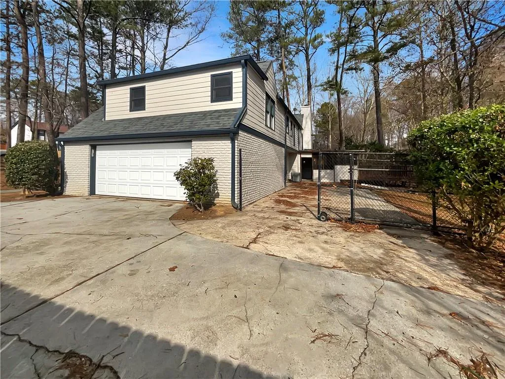 View of property exterior with brick siding, driveway, a gate, and a garage
