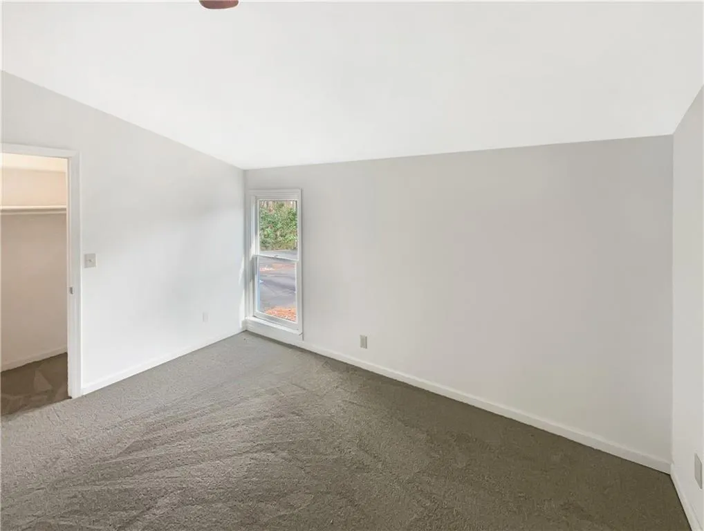Unfurnished bedroom with a walk in closet, carpet, and vaulted ceiling
