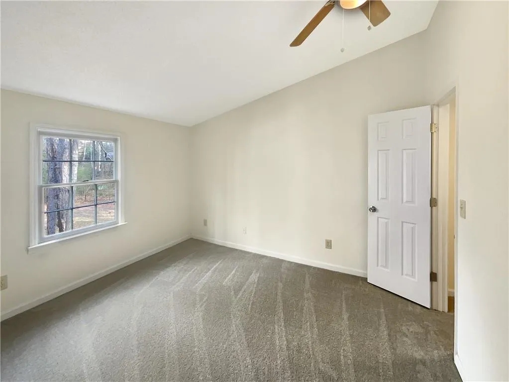 Carpeted spare room with vaulted ceiling and ceiling fan