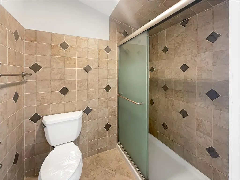 Full bath with a shower stall, tile walls, and vaulted ceiling