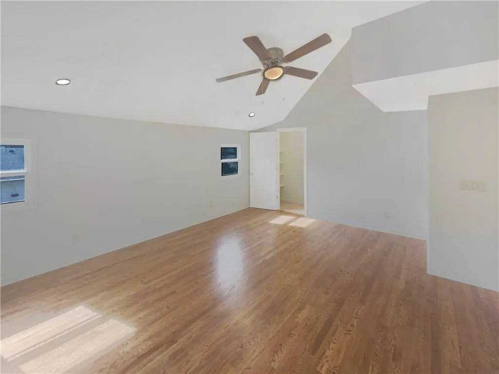 Unfurnished room with vaulted ceiling, light wood finished floors, a ceiling fan, and recessed lighting
