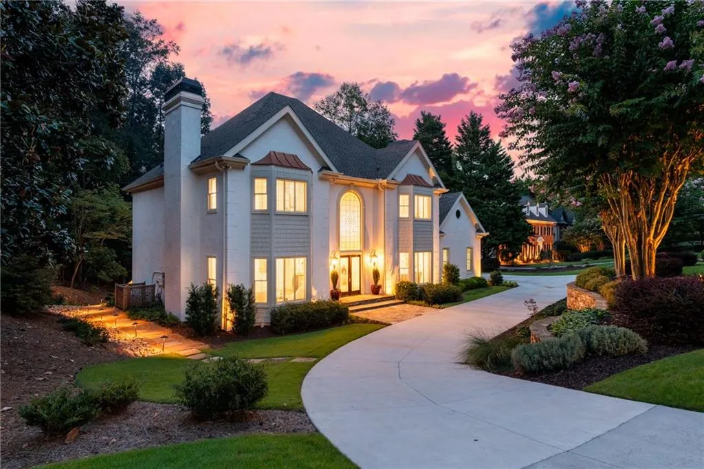 This is an actual at dusk photo - not photoshopped - this executive home radiates elegance with its glowing windows, manicured landscaping, and graceful architecture. The curved driveway and warm exterior lighting highlight its beauty, creating a breathtaking evening presence.