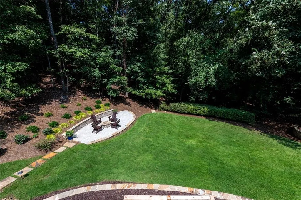View from top of deck to private backyard featuring paver patio with stone fire-pit, manicured grassy area and gorgeous azeleas cover the back. The lot extends pass the azeleas in the back. With a lot size of .6 acres, it's large enough to add a pool if the new homeowner desires.