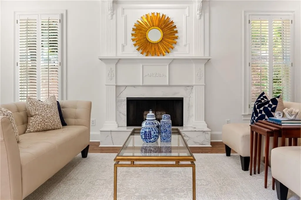Bright living room with fireplace, neutral decor, and natural light from tall Pella windows creates an elegant, welcoming space.