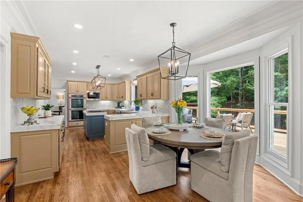 Bright breakfast area seamlessly connected to the kitchen, featuring bay windows, natural light, and warm wood floors perfect for casual dining and entertaining. Excellent view of the deck from large window.