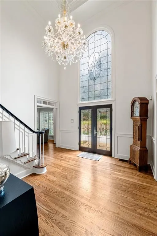 This foyer is a showpiece of elegance and scale, soaring 18 feet high and illuminated by a stunning crystal chandelier that cascades light across the space. A graceful staircase and double mahogany glass doors complete the picture.