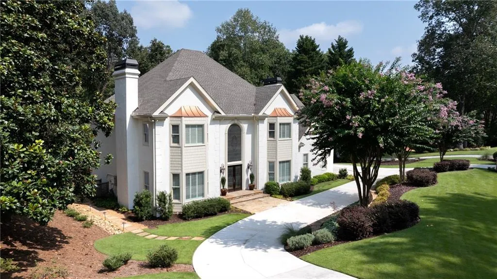 Elegant two-story traditional home with circular driveway, manicured landscaping, and timeless curb appeal in a serene setting.