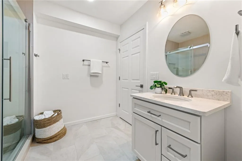 Basement full bath featuring tile shower, quartz vanity with Kohler faucets, and tile flooring. Includes a second laundry room designed for full-size washer and dryer.