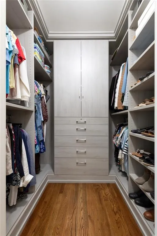 Primary bedroom - her walk-in closet features custom built-ins with soft-close drawers and doors, including a lockable drawer, and pullout full length mirror. Fully adjustable shelving allows for effortless organization and flexibility.