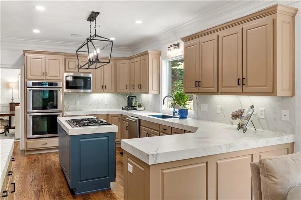 The kitchen offers abundant counter space, with porcelain veining that flows seamlessly from the countertops to the backsplash for a cohesive, elegant look.