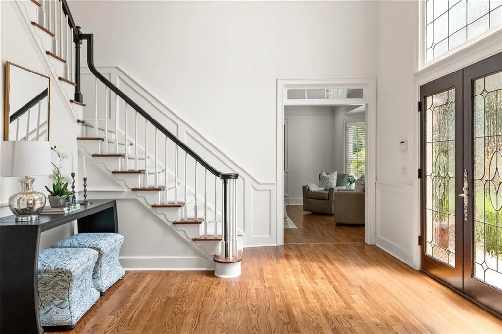 Soaring 18' foyer with hardwood floors, abundant natural light, elegant staircase, and double-height windows creating a grand, inviting entrance that sets the tone for the home.