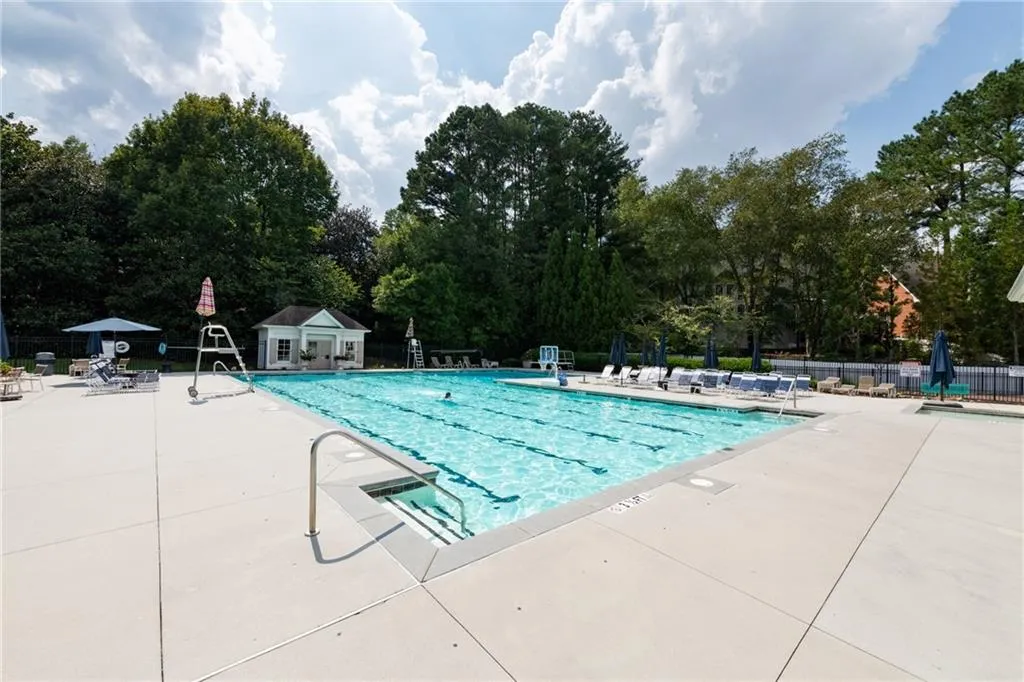 Large community pool includes a diving board and kiddie pool. Pool has plenty of lounge chairs, tables and a pergola.
