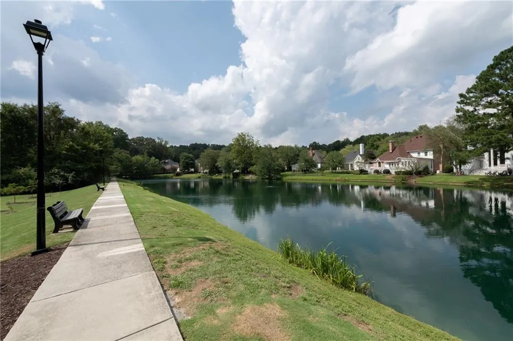 Tranquil community lake with walking path, benches, and scenic views perfect for peaceful strolls, relaxation, and enjoying the natural surroundings.