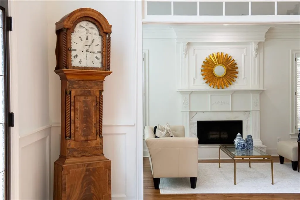 Through the wide entryway, the living room showcases a bright and inviting space with a classic fireplace, elegant millwork, and refined decor accents.
