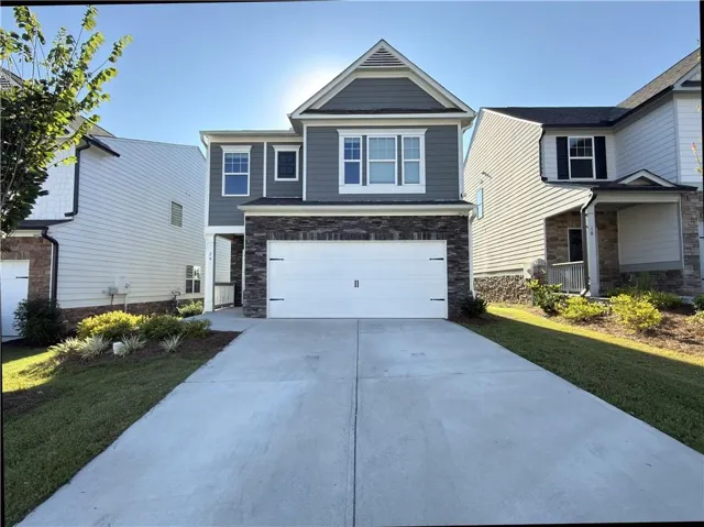 Two-story home with stone veneer and siding facade, attached two-car garage, and concrete driveway