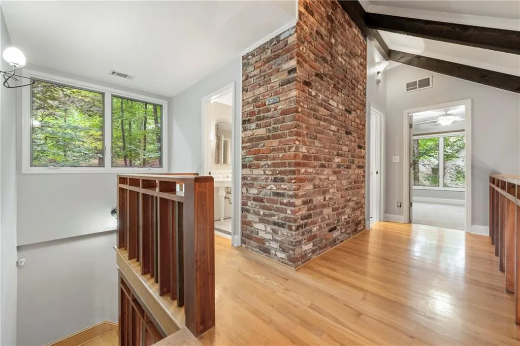 Custom stair railings, even more windows and upstairs catwalk showing fireplace brickwork and beamed ceilings of living room.