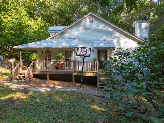 Exterior with horizontal siding, covered front porch, corrugated metal roof, and a prominent chimney
