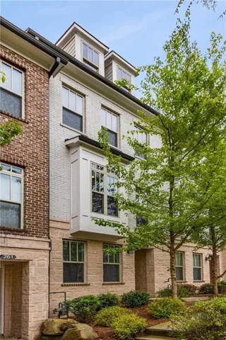 Multi-level exterior featuring a brick and stone facade, dormer windows, and a prominent bay window