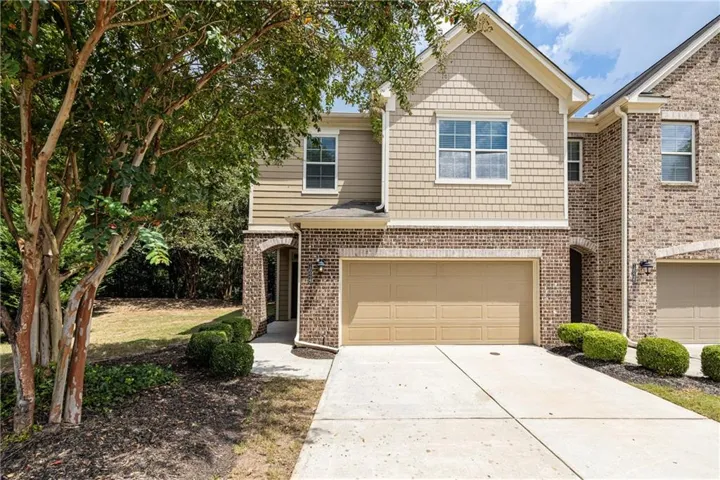Brick and siding exterior with a two-car garage featuring a neutral-toned sectional door