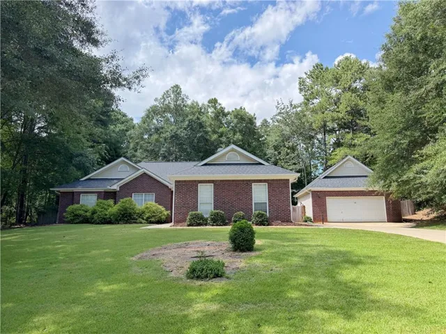 Brick exterior with a detached two-car garage, mature landscaping, and a broad driveway