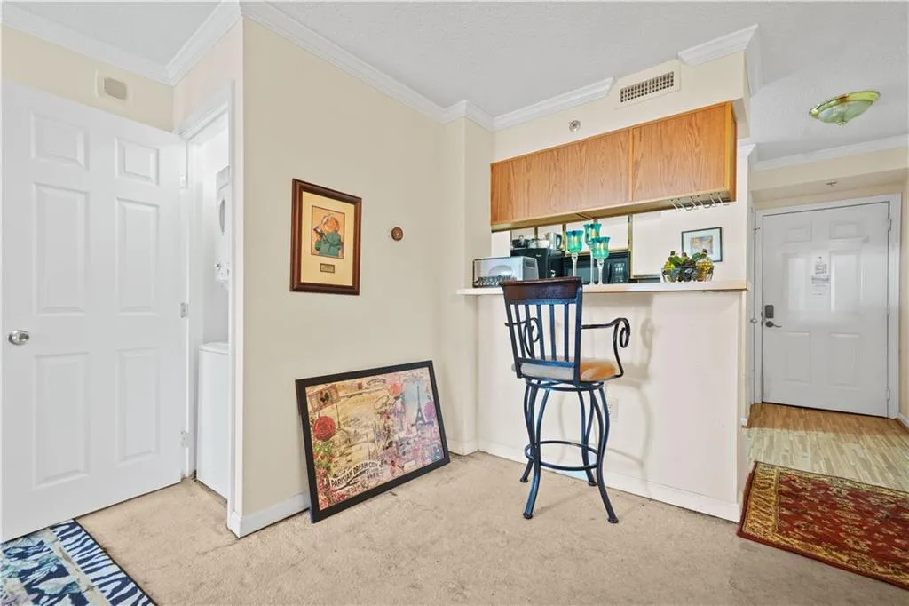 Kitchen with ornamental molding, light carpet, a kitchen bar, brown cabinets, and stacked washer / drying machine