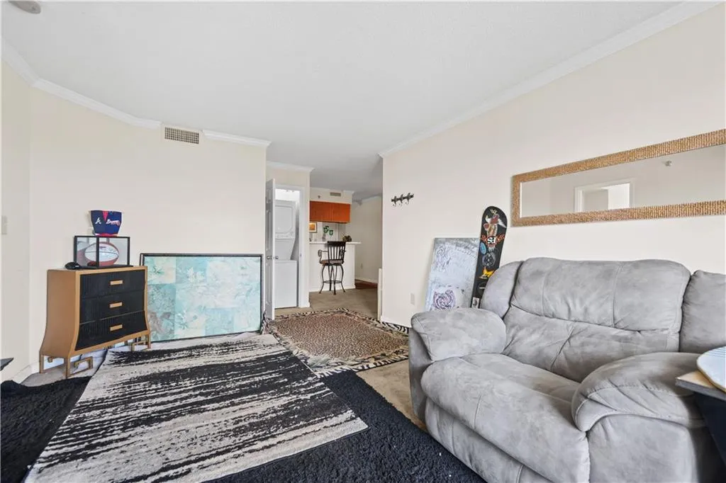 Living room with crown molding, carpet floors, and stacked washer / dryer