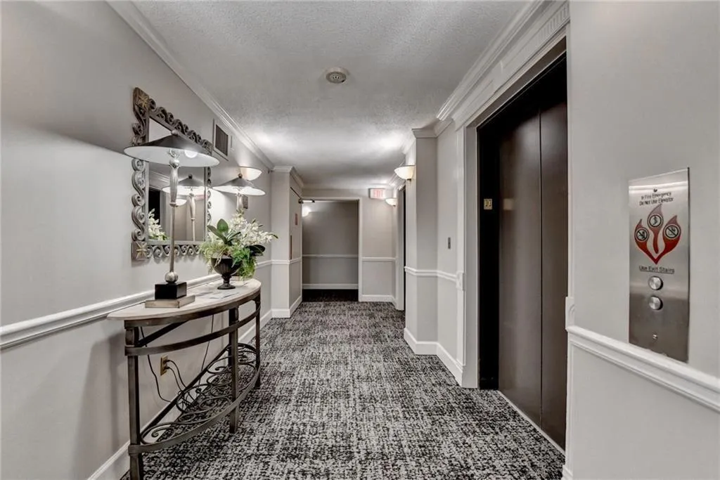 Hallway featuring elevator, ornamental molding, a textured ceiling, and carpet