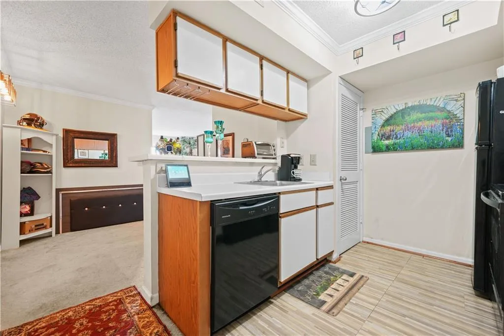 Kitchen featuring ornamental molding, a textured ceiling, light countertops, brown cabinets, and black appliances