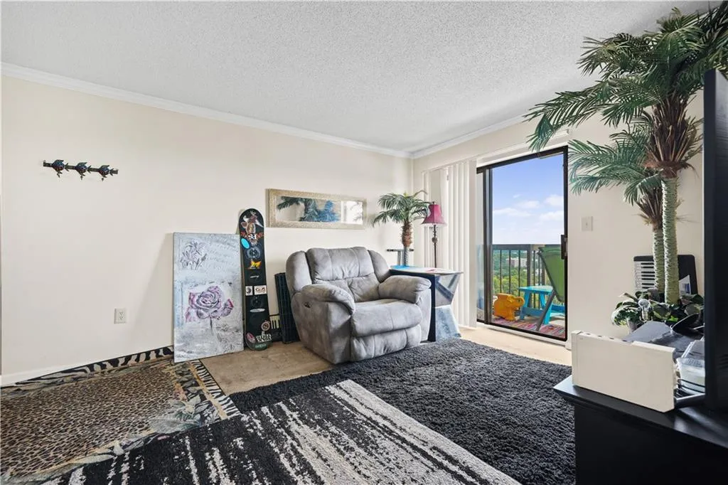 Carpeted living room with crown molding and a textured ceiling