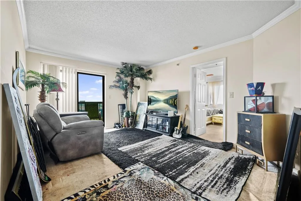 Carpeted living area with crown molding, plenty of natural light, and a textured ceiling