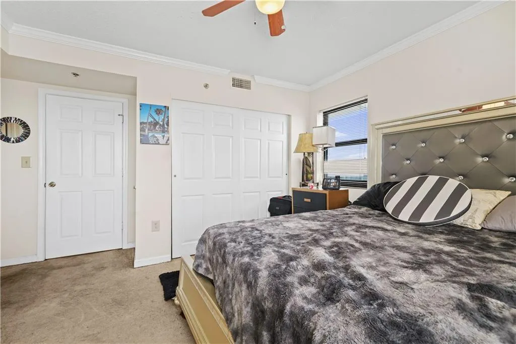 Bedroom featuring crown molding, light colored carpet, a closet, and a ceiling fan