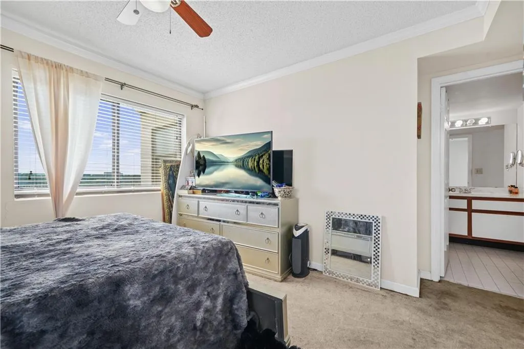 Carpeted bedroom featuring ornamental molding, a textured ceiling, heating unit, and ceiling fan