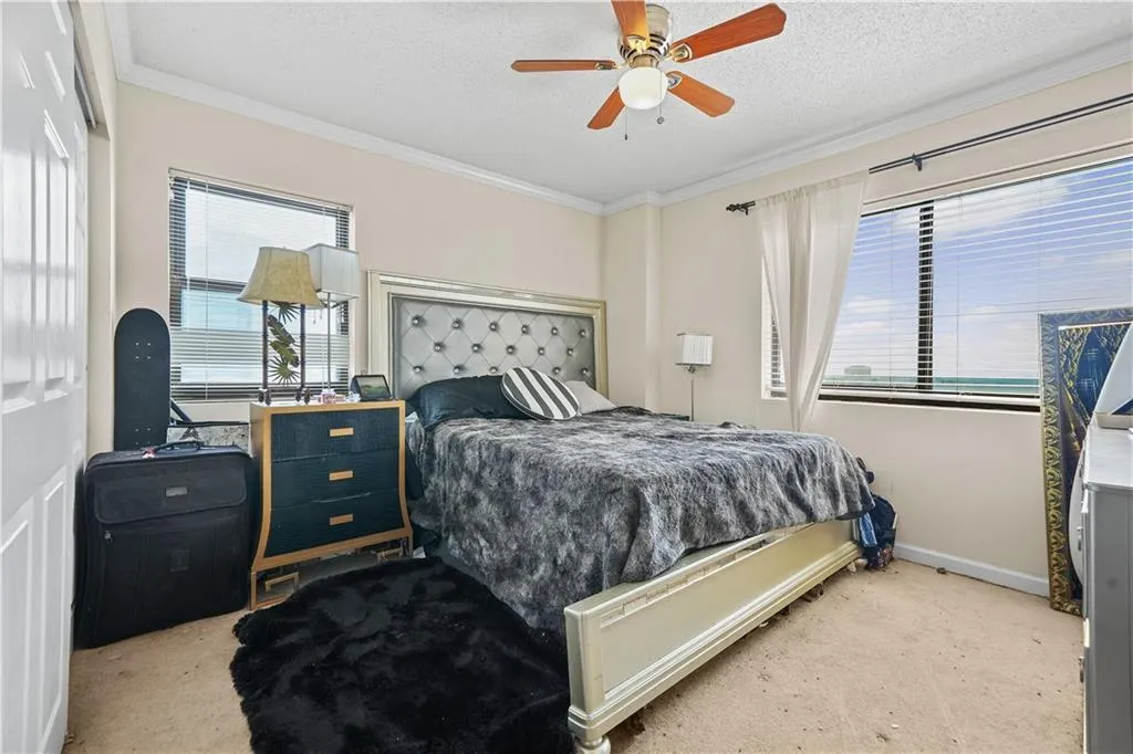 Bedroom with ornamental molding, light carpet, a ceiling fan, a textured ceiling, and washer / dryer