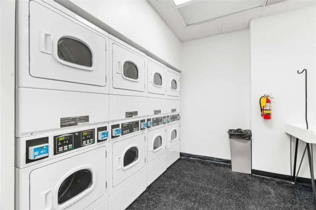 Washroom featuring stacked washer and clothes dryer and dark carpet