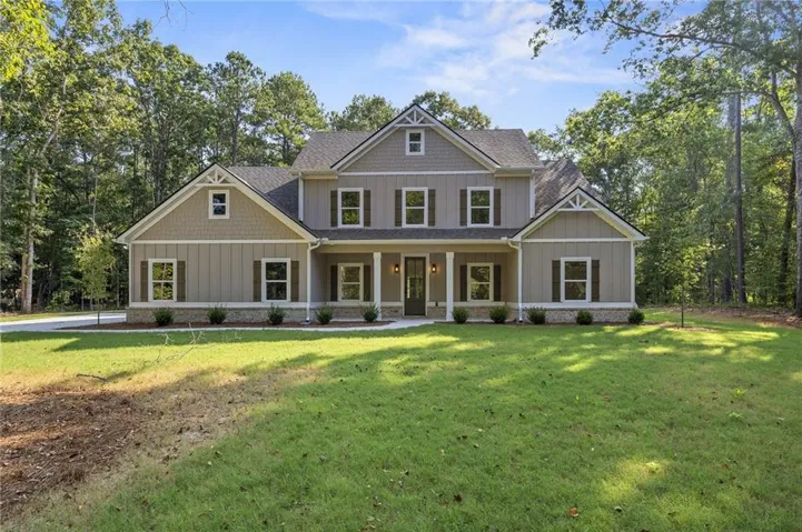 Two-story property with a gabled roofline, board and batten siding, stone-front detailing, and a covered porch