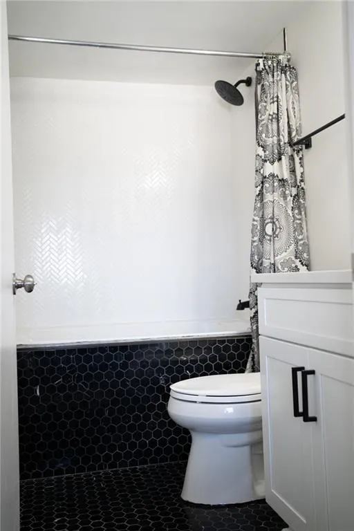 Bathroom with tile patterned floors, vanity, shower / tub combo, and tile walls