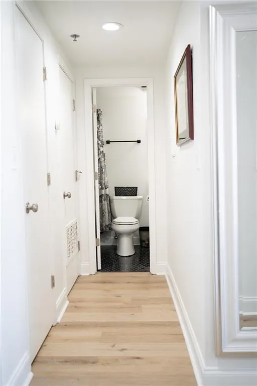 Entry/hallway with Bathroom access featuring light wood-style flooring, curtained shower, and recessed lighting