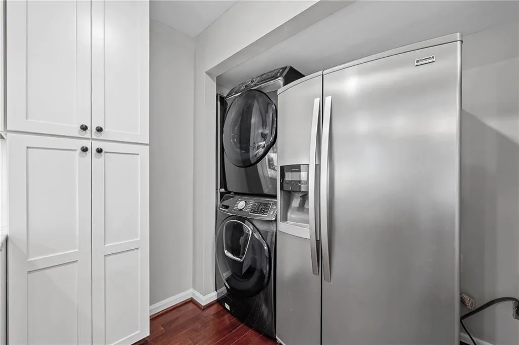 Laundry area with dark wood-style flooring and estacked washer and dryer