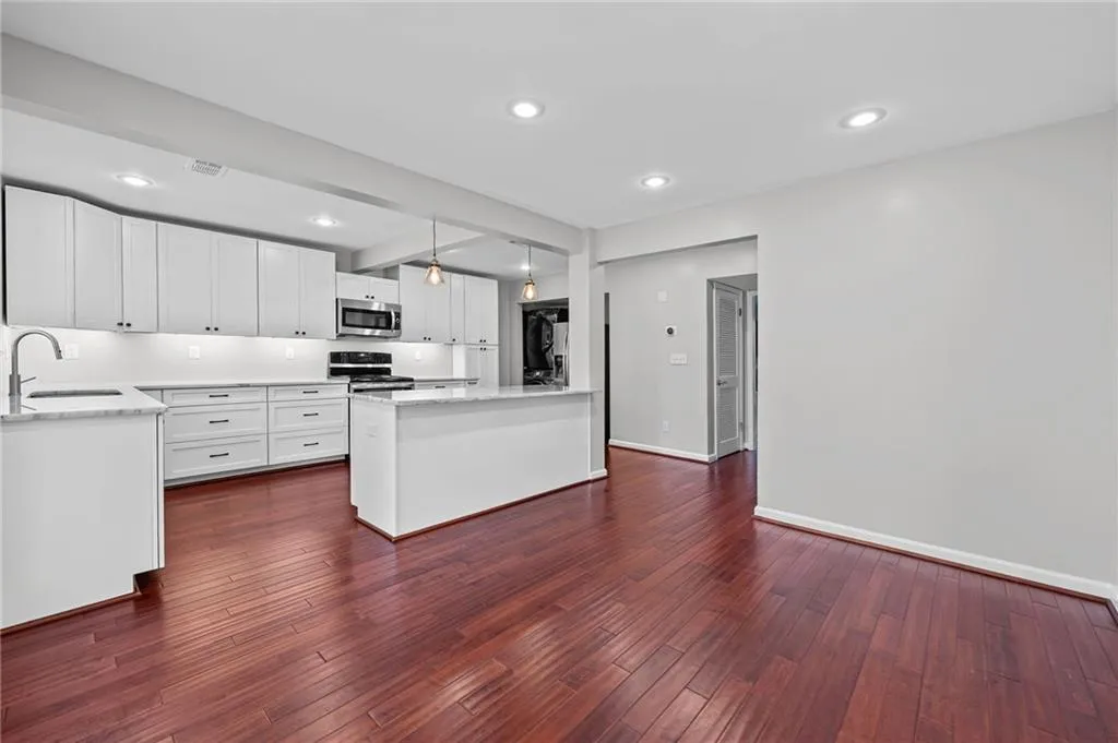 Kitchen with hanging light fixtures, white cabinets, recessed lighting, beamed ceiling, and appliances with stainless steel finishes