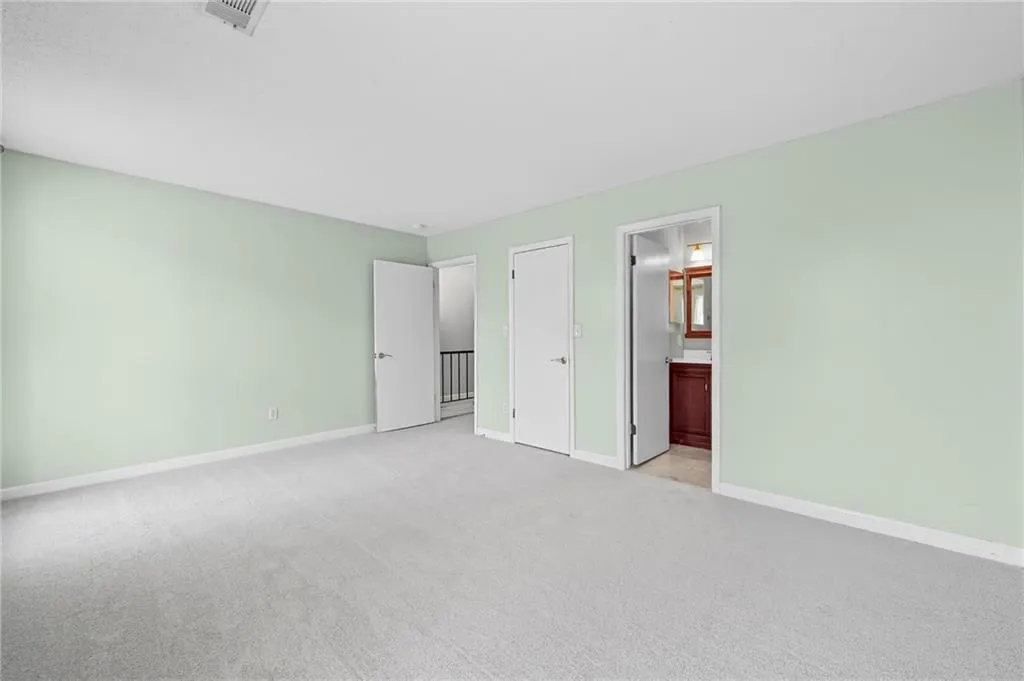 Unfurnished bedroom with light colored carpet and connected bathroom
